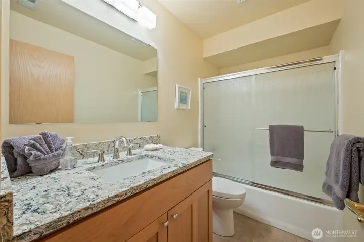 Guest Bathroom – Full Bath with Updated Vanity  Bright full bathroom featuring a granite-topped vanity, undermount sink, and tub/shower with sliding glass enclosure.