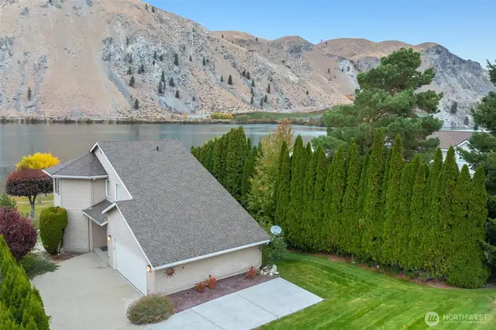 Beautiful aerial perspective of the home set against dramatic Columbia River cliffs. Highlights the quiet cul-de-sac location, manicured lawn, and direct proximity to Sun Cove’s waterfront greenbelt.