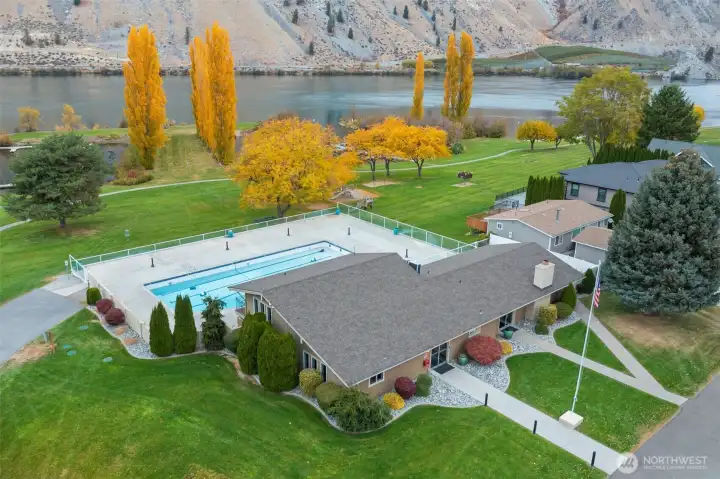 Aerial view showing Sun Cove’s community pool, clubhouse, and expansive greenbelt stretching down to the sandy waterfront along the Columbia River.