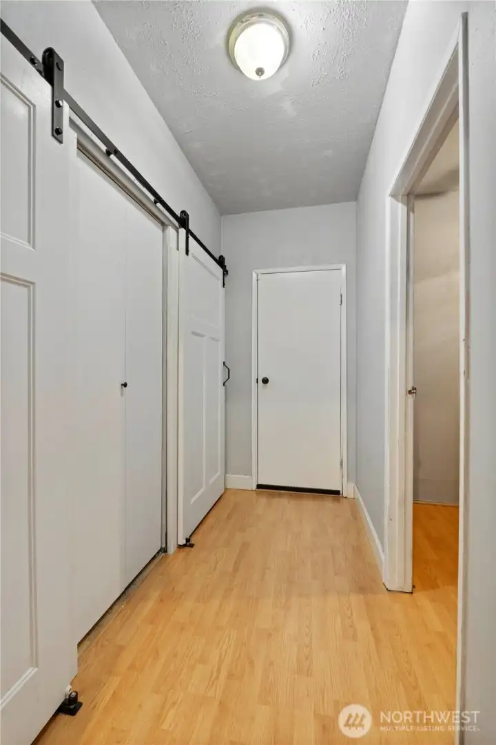 Hallway leading to the garage offers laundry space on the left and the entrance to a finished room on the right.