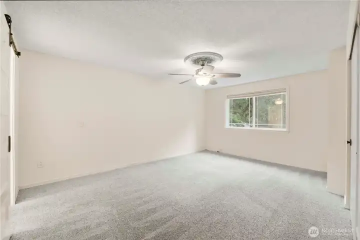 Spacious primary bedroom with ceiling fan.