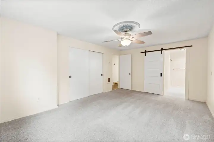 Another view of the primary bedroom showing the stylish barn door leading to the private bath.