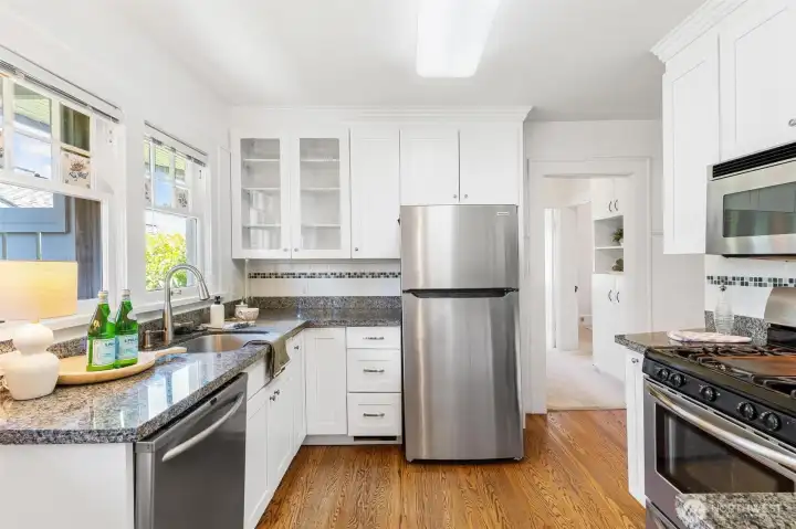 Beautiful, sun-filled kitchen featuring stainless steel appliances and a gas stove. This space boasts classic details and is perfectly prepared for your next culinary creation.