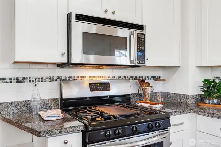 Stainless steel four-burner gas cooktop with an integrated griddle and built-in microwave.