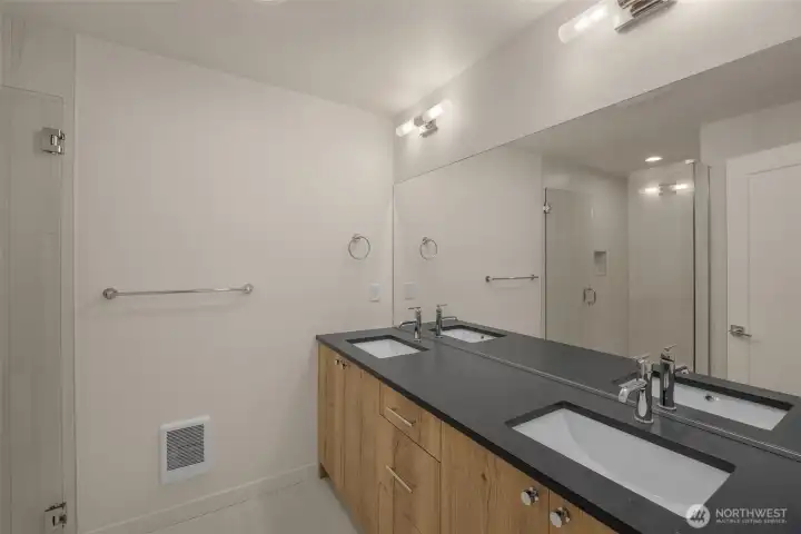 The spa-like primary bath features a dual-sink vanity with sleek hardware and wood-toned cabinetry.