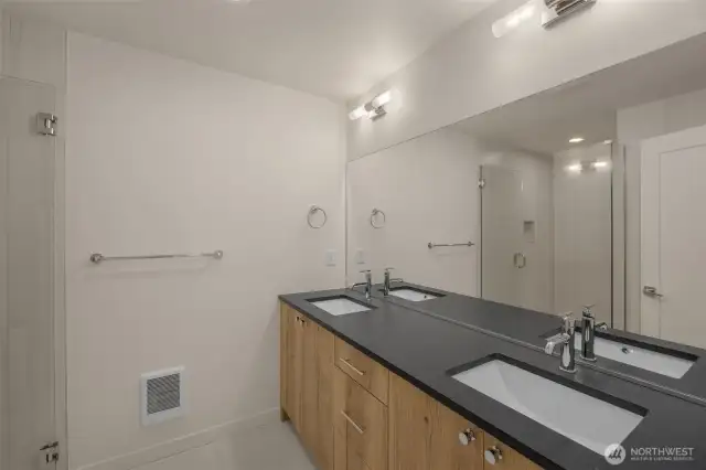 The spa-like primary bath features a dual-sink vanity with sleek hardware and wood-toned cabinetry.