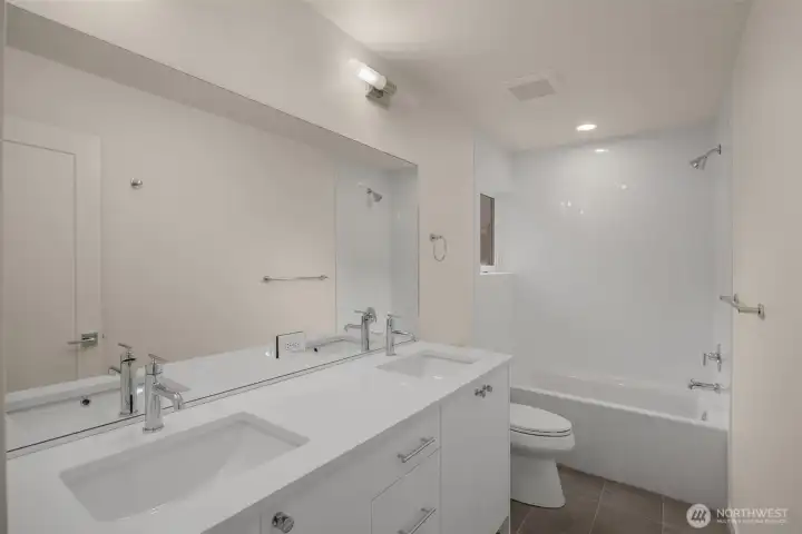 A full-sized second bath with dual sinks and a tub-shower combo is ideal for shared living.