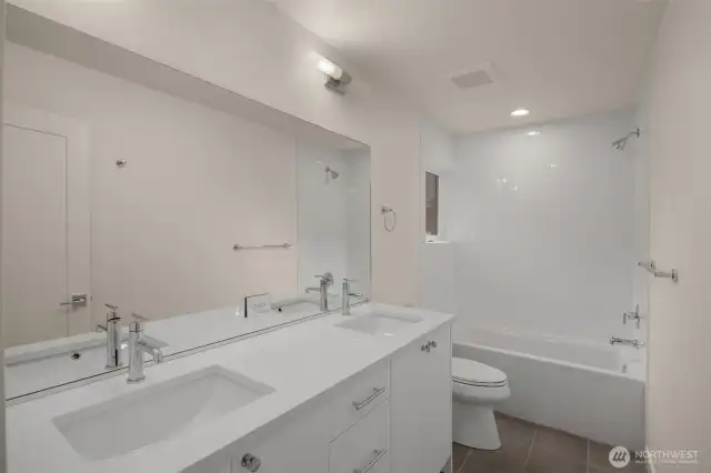 A full-sized second bath with dual sinks and a tub-shower combo is ideal for shared living.