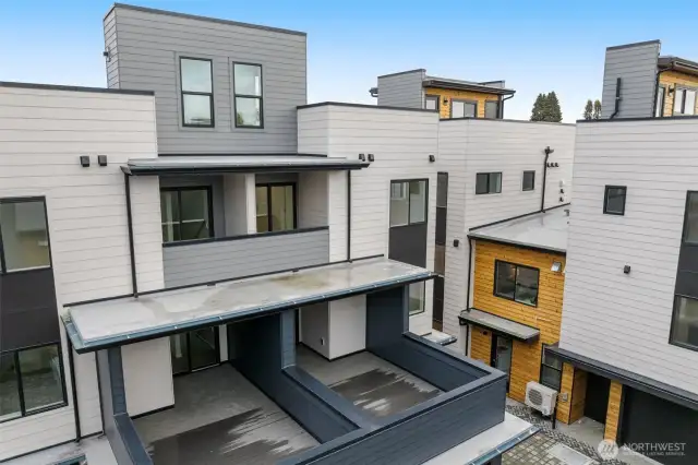 A rear view of the home reveals the spacious dual patio design and clean, modern architecture.