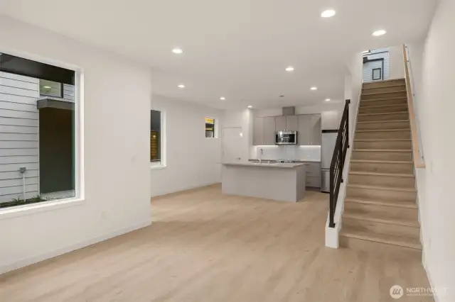 The open living space connects seamlessly to the kitchen and dining—stylish, spacious, and soaked in light from every angle.