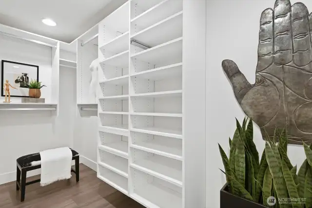 A huge walk-in closet with room for another bureau or dresser, extra large mirror & seating.