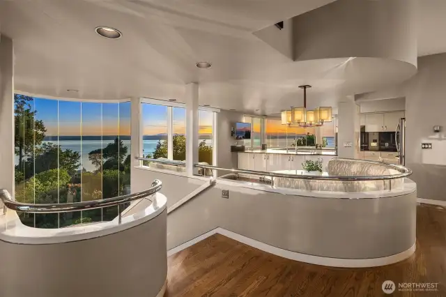 The interior curves soften the straight lines of the home; this also heightened by the choice of natural materials, finishes and colors: oak floors, metal railings, cream and dove tones... a soothing design which doesn't distract from the outdoor spectacular scenery.