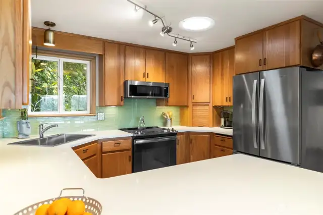 Beautifully remodeled kitchen with quartz countertops, glass tiling and eating space