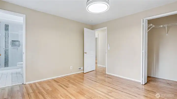 Another view of the primary with glimpses of the closet and en-suite bathroom.