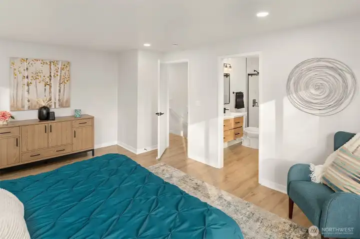 Large primary bedroom with ensuite 3/4 bath on the main floor, staged with a king size bed.