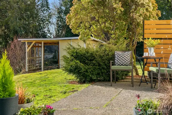 Concrete patio off rec room provides access to grassy back yard and large, separate shed.