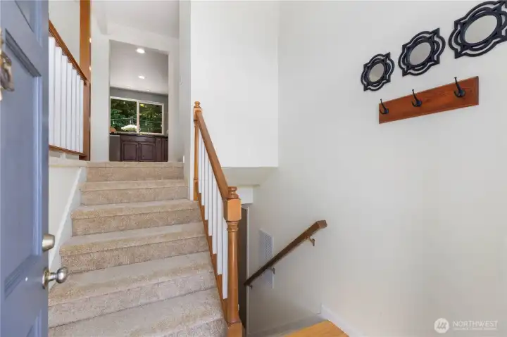 A welcoming split-entry with warm wood railings and carpeted staircase, offering a glimpse into the bright, open main level above.