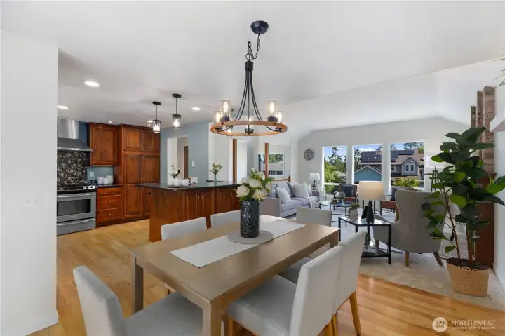 Bright and open dining area with warm hardwood floors, a statement wagon-wheel chandelier, and a seamless flow into the kitchen and living room, a natural hub for everyday meals and gatherings.