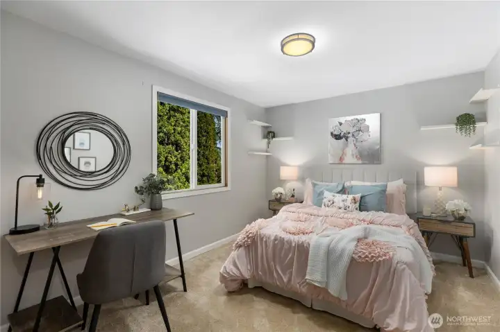 A well-proportioned secondary bedroom with soft carpet, a framed window with lush tree views, floating wall shelves, and room for both sleeping and a workspace, comfortable and versatile.