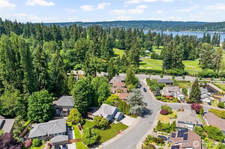 Elevated drone view showcasing the surrounding Kenmore neighborhood with a golf course and Lake Washington visible in the background, highlighting the area’s exceptional natural setting and proximity to premier recreational amenities.