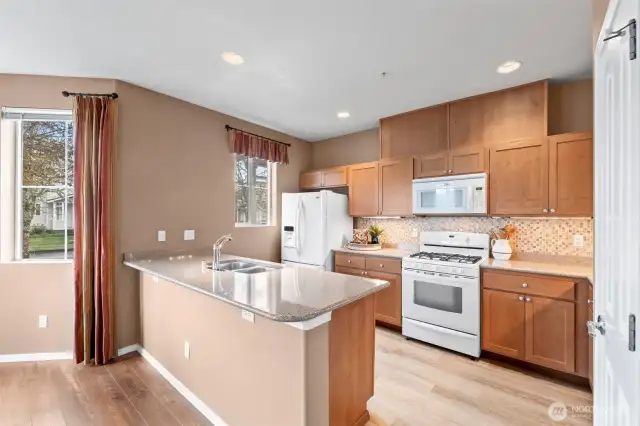 Beautiful and spacious updated kitchen featuring wide granite countertops and tile backsplash. All appliances stay.