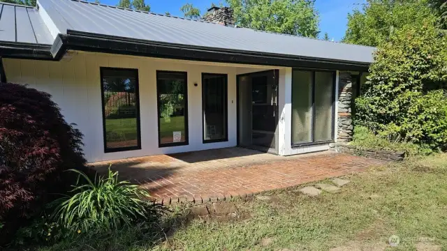 Front view of home with ADA access, mature landscaping and nice brick patio throughout