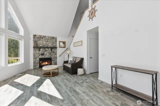 Living room with cathedral ceiling & cobblestone propane fireplace to stay cozy on cold evenings.
