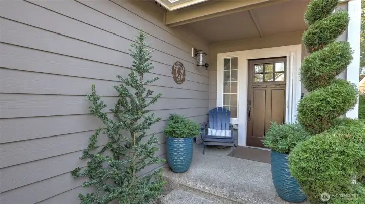 Welcoming front entry with charming greenery, stylish planters, tranquil water feature, and a cozy seating nook that sets the tone for the home.