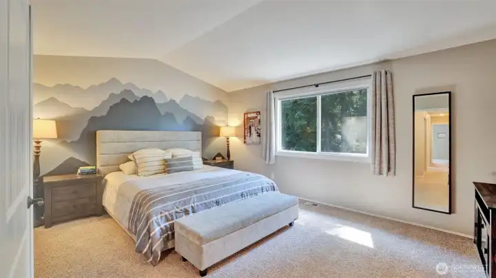 Retreat to this spacious primary bedroom upstairs filled with natural light, featuring a large window and an eye-catching accent wall.