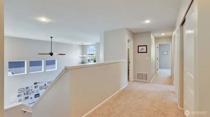 Upper-level hallway offers an open view overlooking the living area and direct access to multiple bedrooms just steps from the primary suite.
