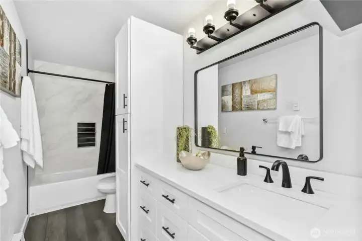 Remodeled bathroom with LVP flooring, new cabinets with quartz counters