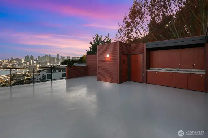 Large rooftop deck has built in cabinets, a kitchen sink, and storage shed