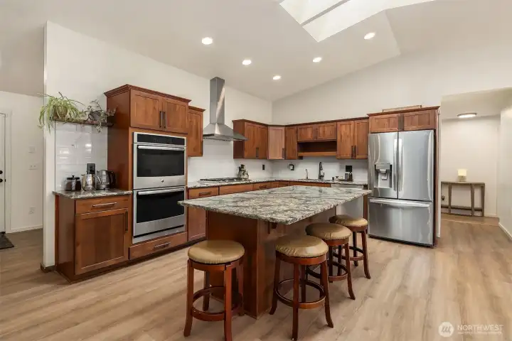 The stylish chef’s kitchen features top-of-the-line stainless steel appliances, custom solid wood soft-close cabinetry, three skylights, a spacious island, and a generous walk-in pantry