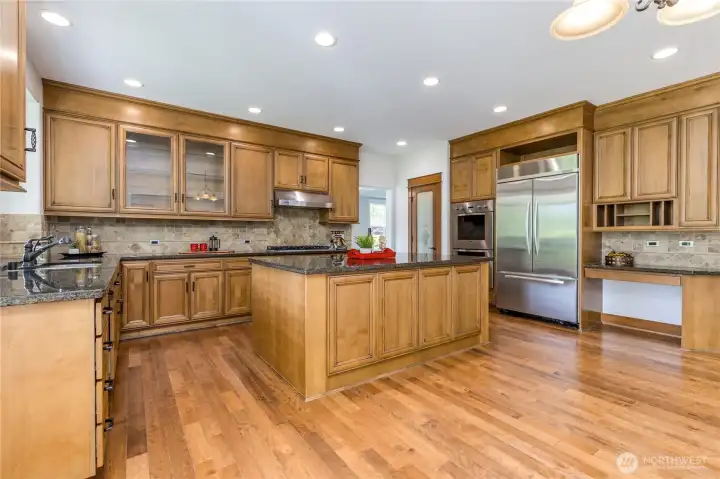 Chef’s kitchen featuring stunning granite countertops, warm wood cabinetry, and a beautiful tile backsplash.