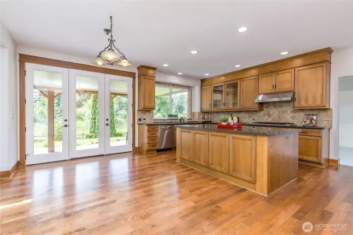 Light-filled kitchen and casual dining area, featuring beautiful hardwood floors and French door access to the outdoor patio for a seamless indoor-outdoor lifestyle.