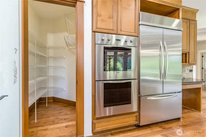 Chef-inspired kitchen amenities featuring a high-end Viking refrigerator and double oven, perfectly complemented by a spacious, organized walk-in pantry.