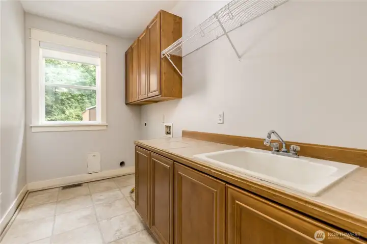 Well-appointed laundry room conveniently located just off the garage, featuring a utility sink and ample cabinetry for organized storage.