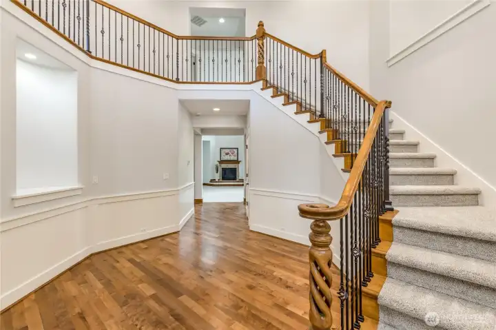 Grand two-story hall featuring elegant wainscoting, sophisticated railing, and dedicated wall niches perfect for showcasing your favorite art or decor.