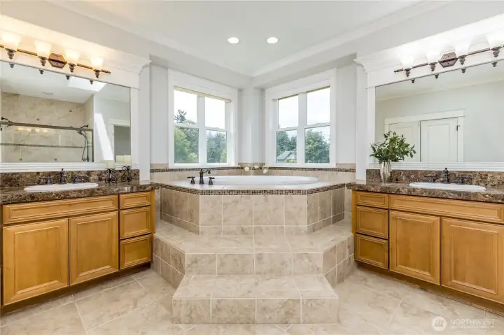 Unwind in your own private oasis: This primary bathroom features a deep soaking tub, dual vanities and beautiful tile accents creating a serene, spa-like retreat at the end of the day.