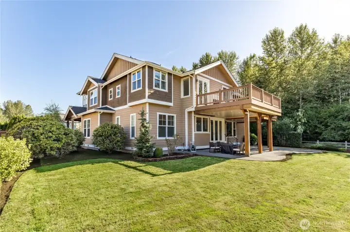 Stunning rear exterior view highlighting the seamless connection between the home and its peaceful, park-like backyard.