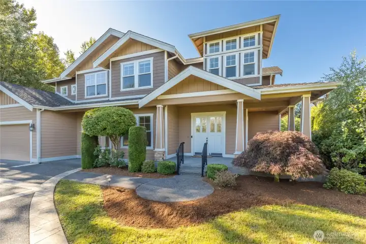 Stately front elevation of this move-in-ready home, featuring timeless design and a charming, covered entrance, perfectly situated in the peaceful Alder Meadows community.