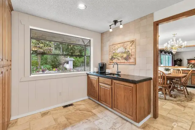 The wet bar area looks out at the beautiful backyard through the the large garden window.  To the left are floor to ceiling built in cabinets which offer tons of storage.