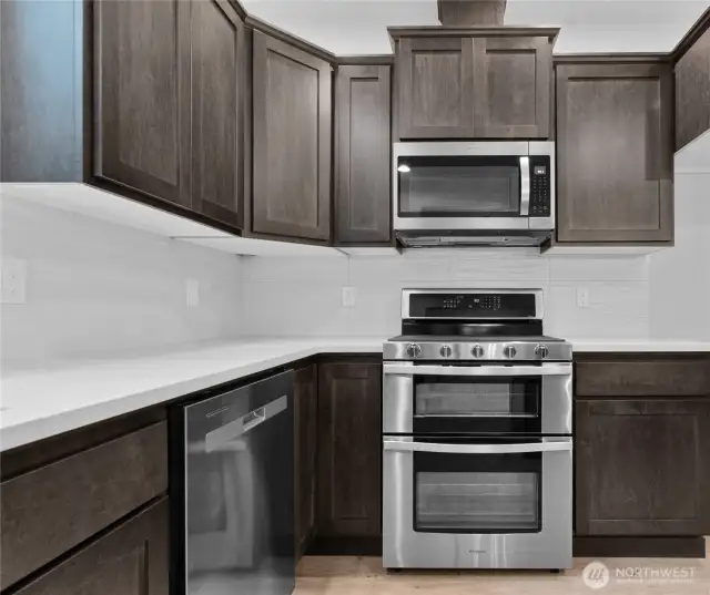 Sleek stainless steel Whirlpool appliances include a microwave, gas double oven and dishwasher.