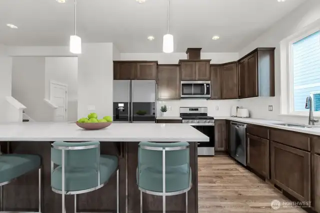 Gathering around the kitchen island is perfect for quick snacks and friendly chats. Photo is virtually staged from same plan on different lot, for reference only.