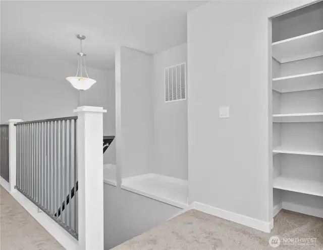 View from 2nd floor landing of stairwell with open rails and decorative art ledges, plus a handy closet.