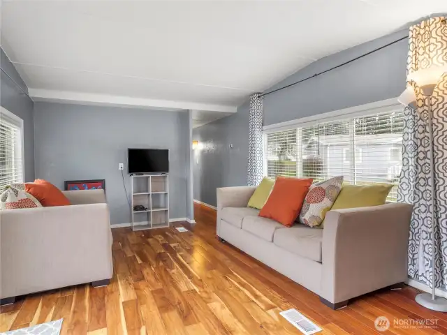 Living room space offers laminate floors, neutral paint colors and upgraded windows offering plenty of natural light.