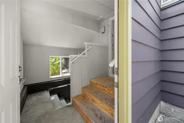 The stairs off of the laundry area head down to the basement.