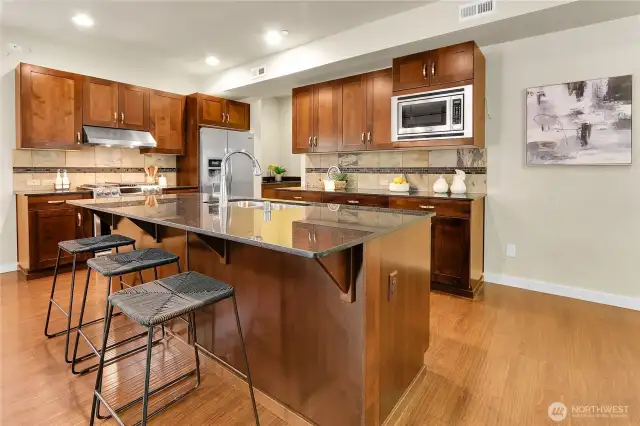 The palatial kitchen is a chef’s dream and features a gigantic granite slab center island with a long dining bar, a double stainless steel sink, and cabinets and drawers tucked underneath.