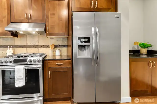 Stainless steel appliances highlight the kitchen; including a four burner gas cooktop with a griddle in the middle, and a  café door refrigerator with water & ice on the door.