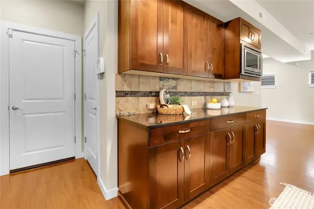 Across the walkway from the pantry, and next to the refrigerator, is a food staging area that has an additional countertop with cabinets below.  It's a dedicated spot for plating or arranging dishes before they are presented to the table.